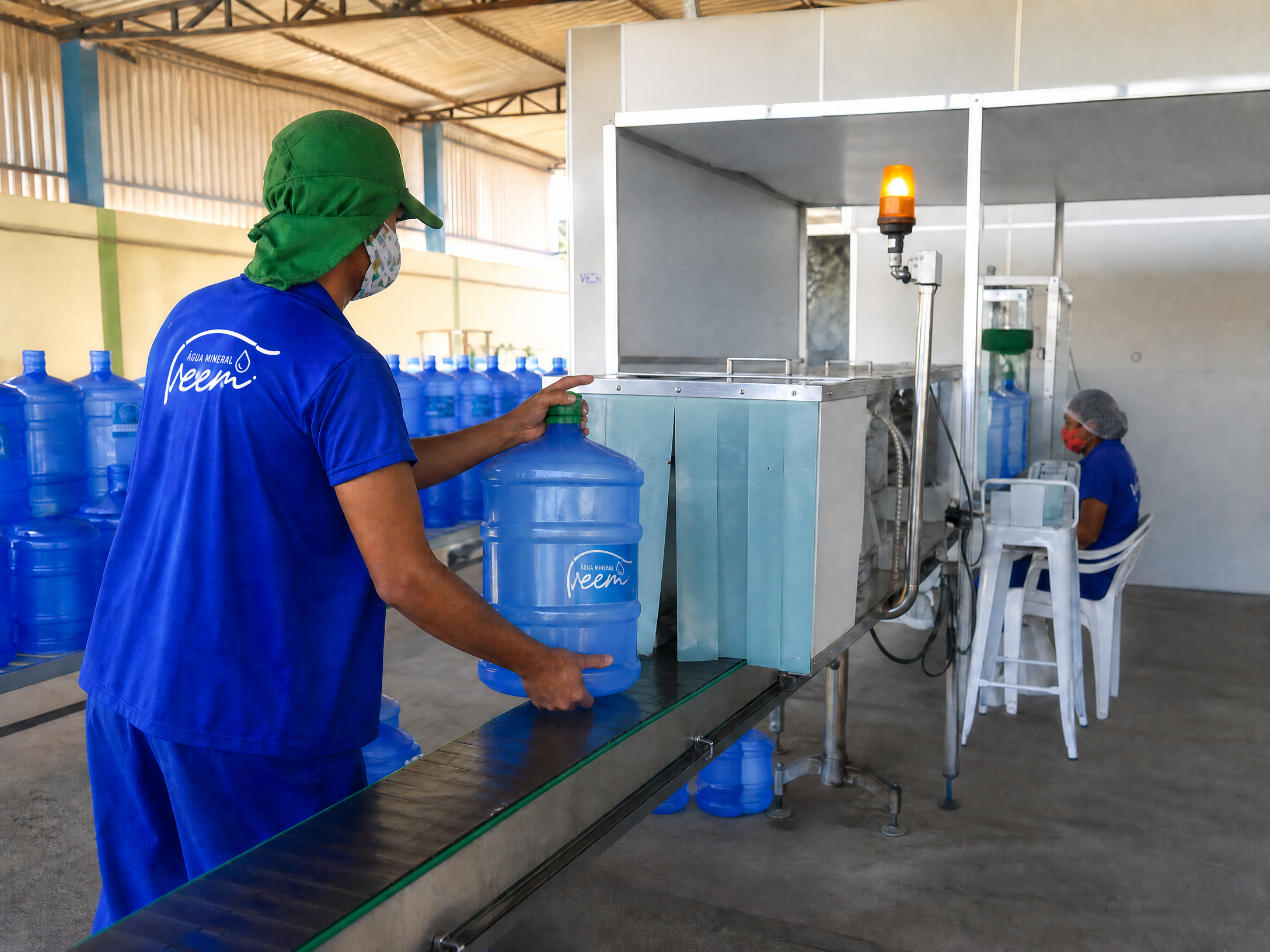 Funcionário Veem conduzindo um galão na linha de envase